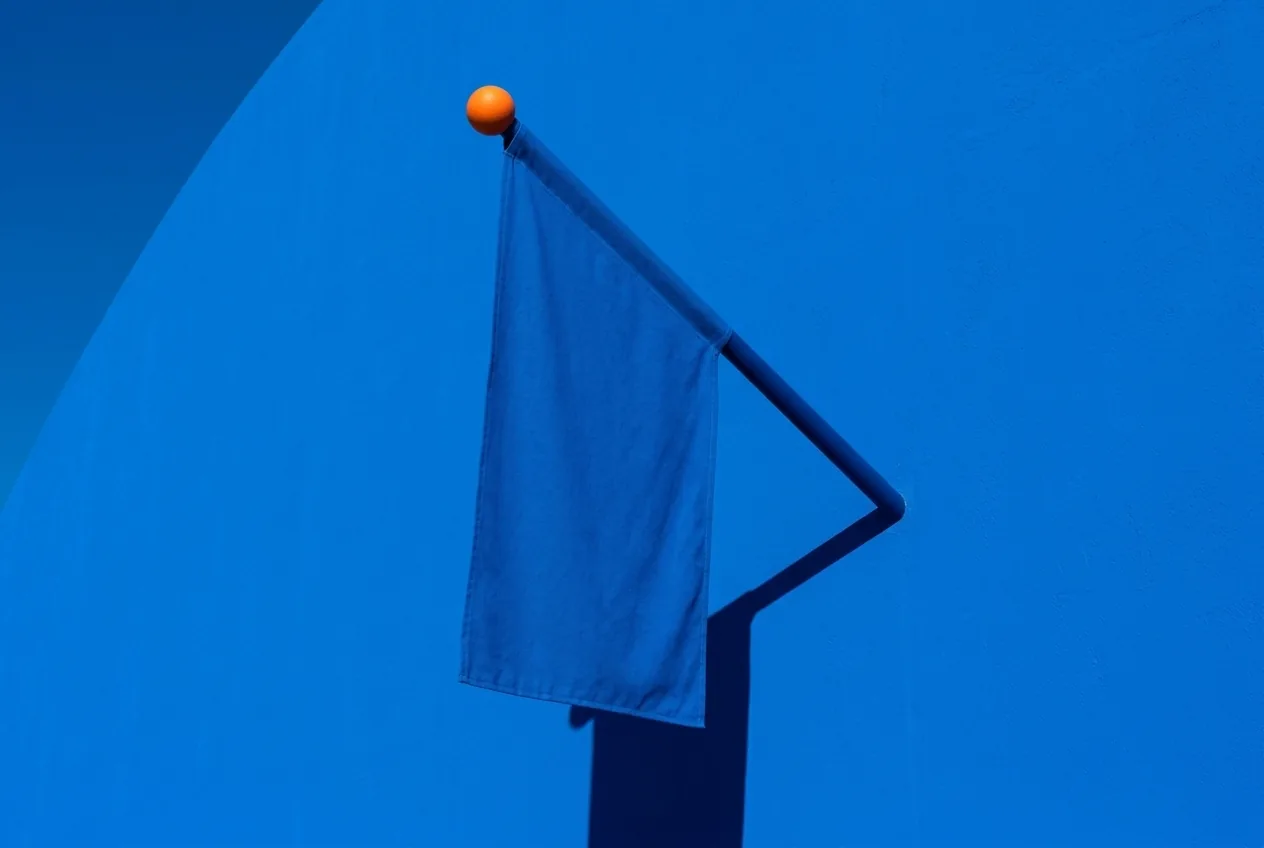 Banderín azul con remate naranja sobre una fachada azul