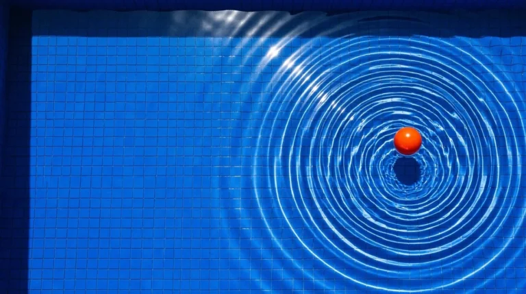 Ondas concéntricas en una piscina azul alrededor de una pelota naranja