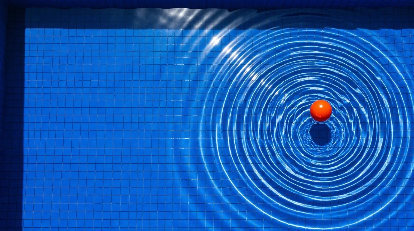 Ondas concéntricas en una piscina azul alrededor de una pelota naranja